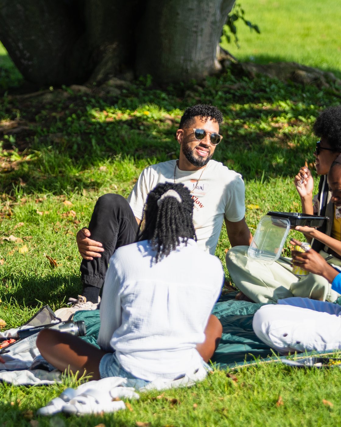 Nolan Krueger smiling while seated in a circle on the grass with community members at Flourish & Flow.